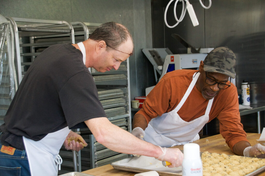 Two bakers working together to lay out cookies.